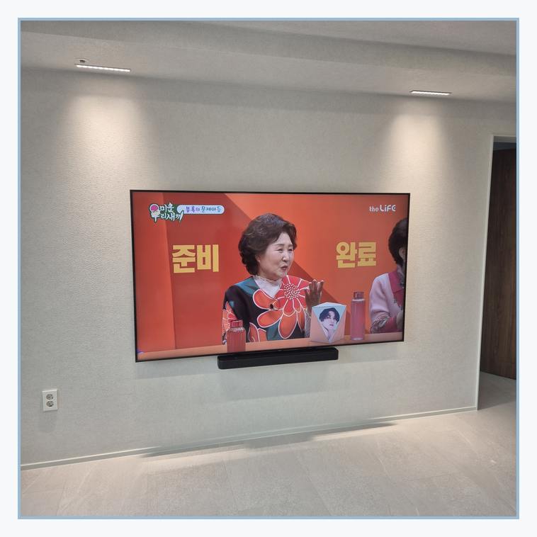 거실 화면 배치를 검토하는 벽걸이TV 설치 참고 사진 · 화면 폭과 무게 확인